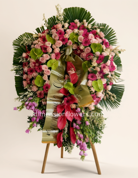 Corona funebre grande con fiori pregiati (rose, peonie, orchidee ecc)colore tonalità rosa.